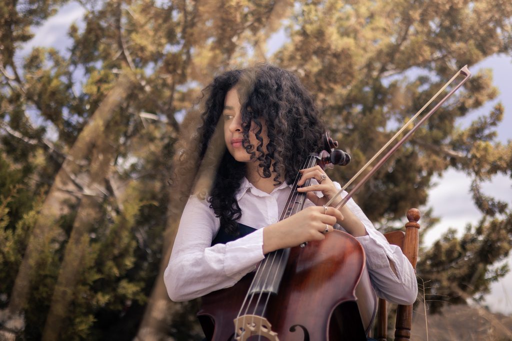 Untersicht von junger Frau die Cello im Freien spielt