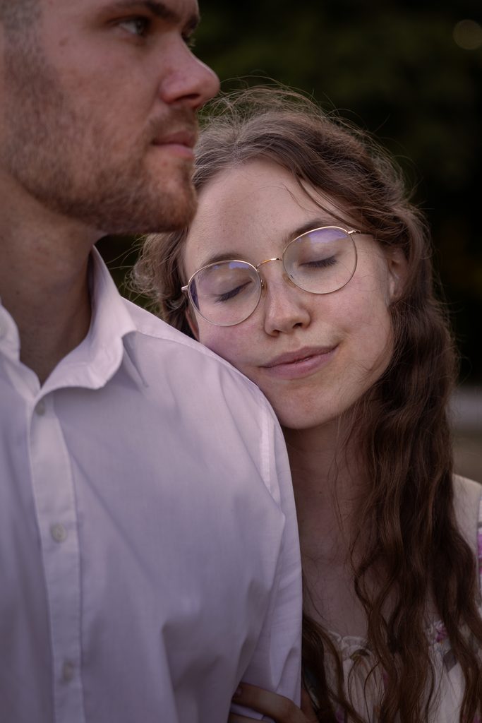 Künstlerische Aufnahme einer jungen Frau die sich verträumt an die Schulter ihres Partners lehnt