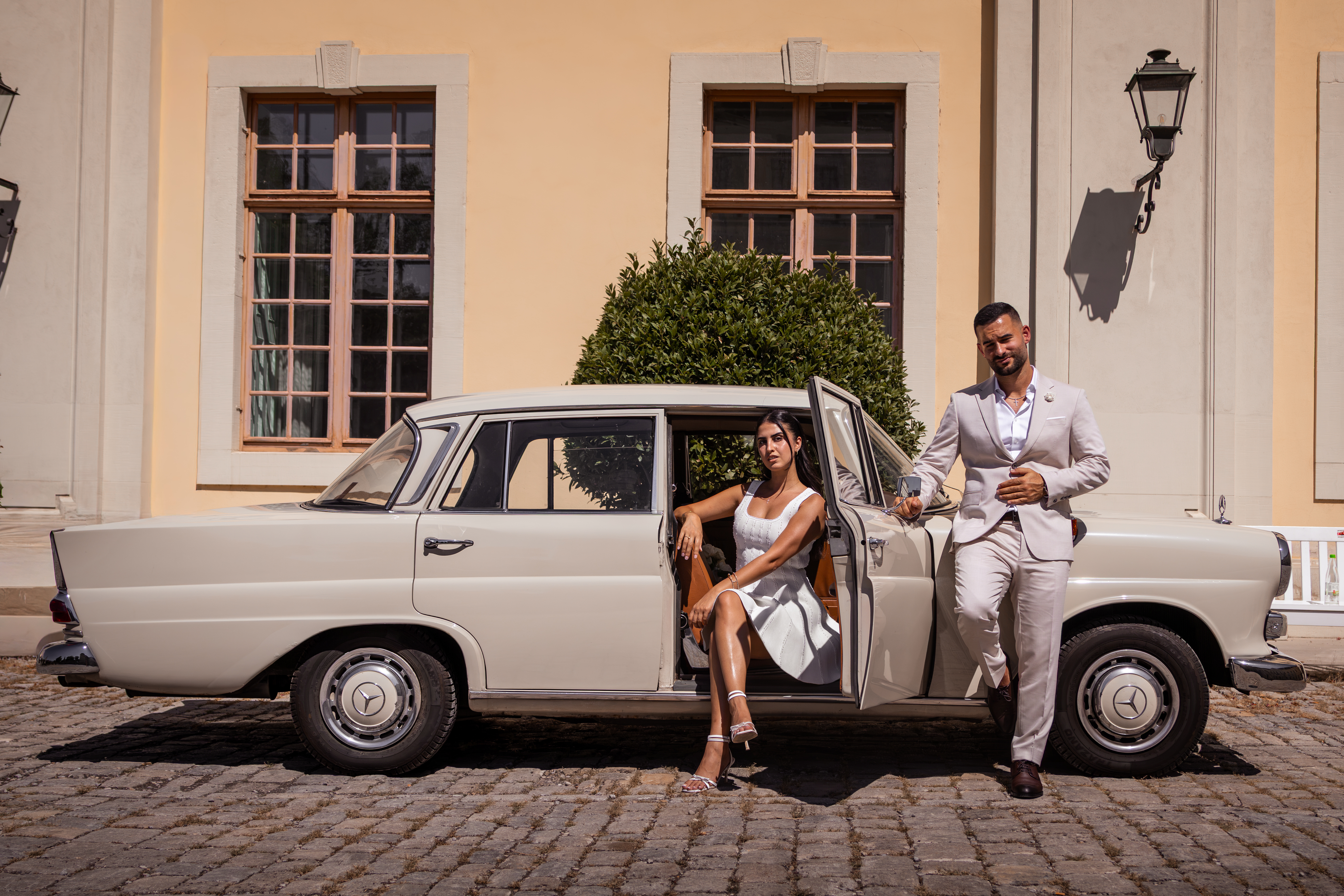 Hochzeitspaar posiert elegant neben einem klassischen Oldtimer