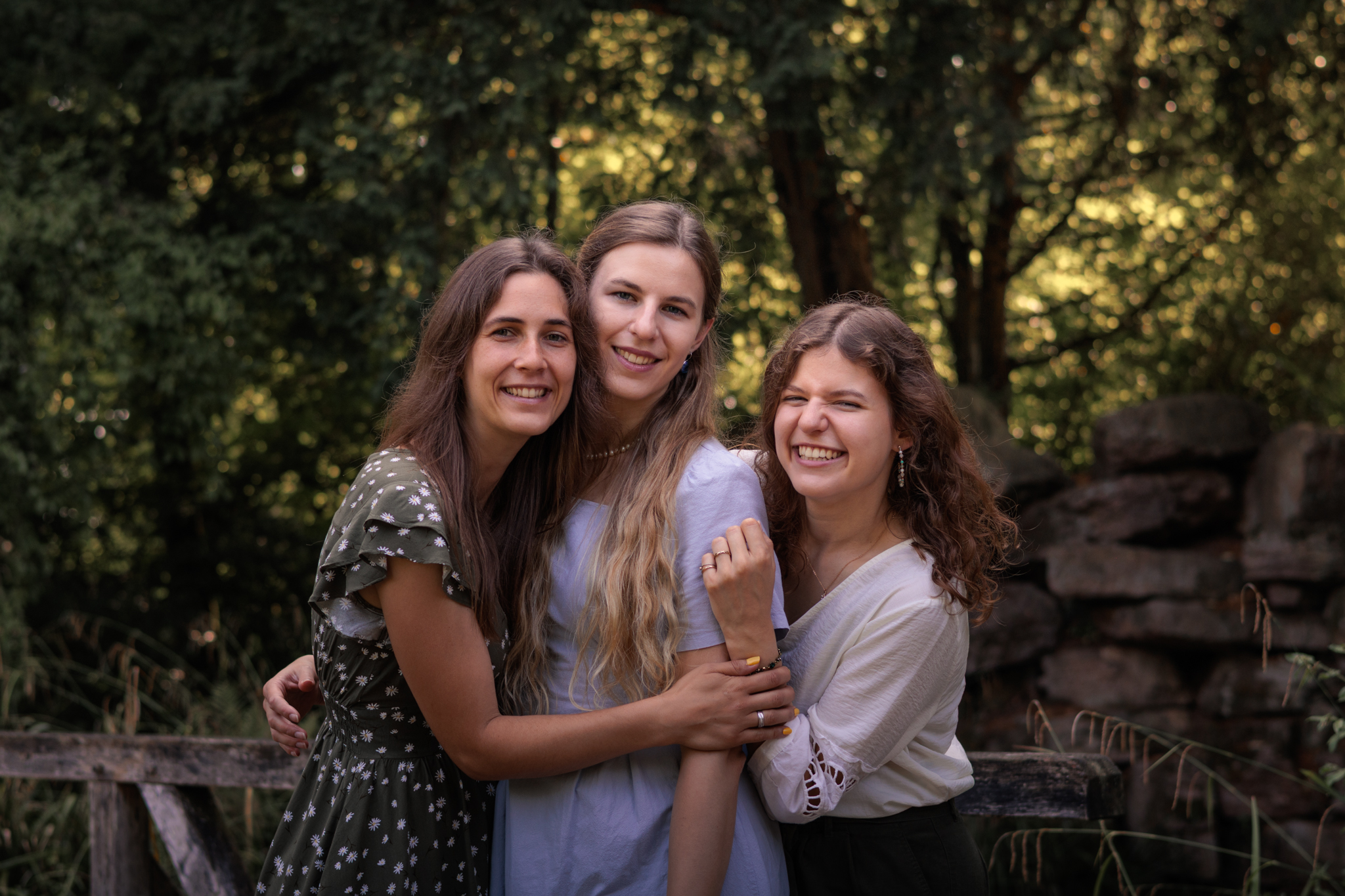 Drei Frauen umarmen sich lachend bei einem Familienfotoshooting im Grünen